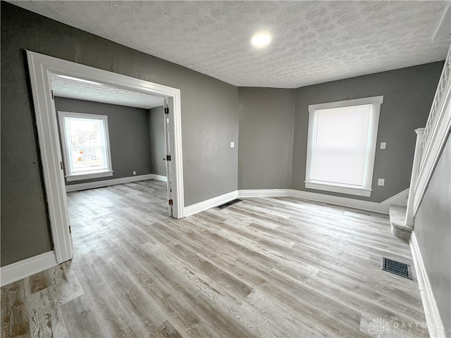 unfurnished room with light wood-type flooring and a textured ceiling