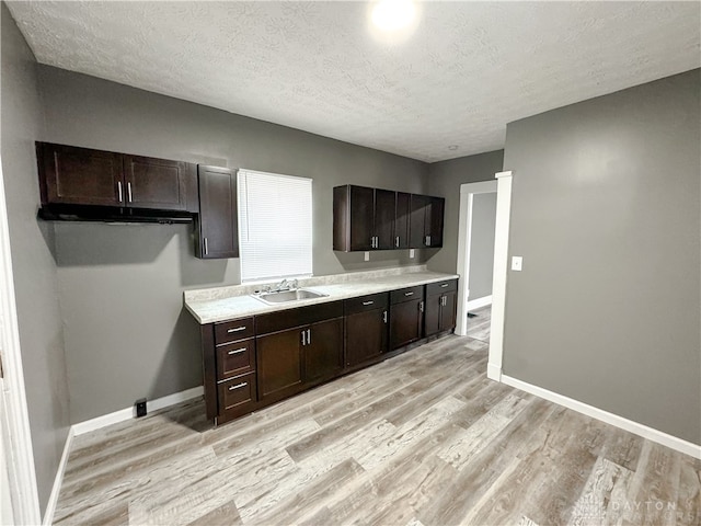 kitchen featuring a textured ceiling, light wood-type flooring, and sink