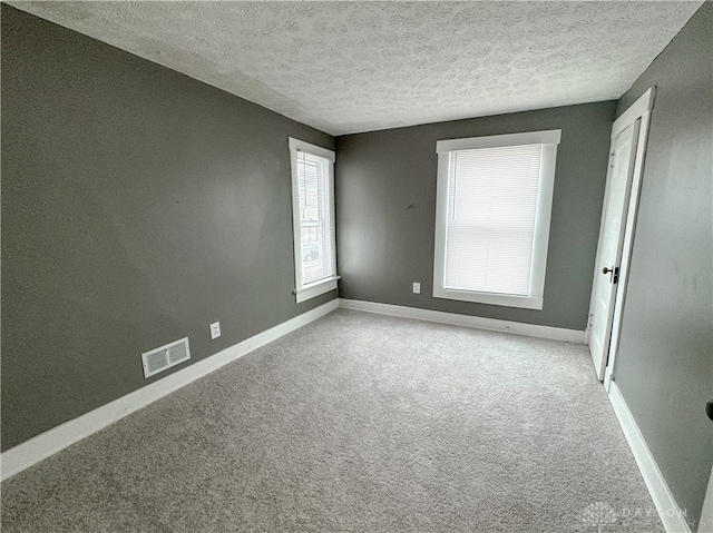 carpeted spare room with a textured ceiling