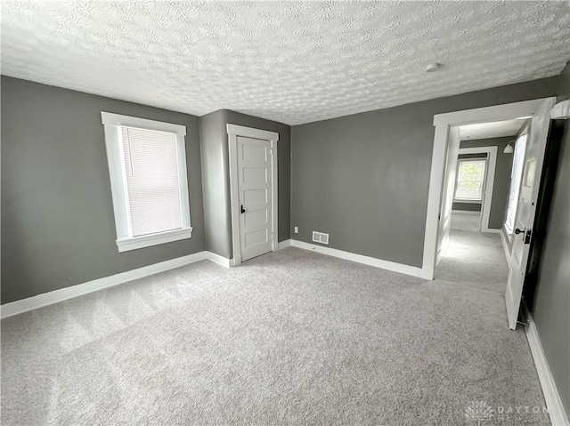 unfurnished bedroom featuring a textured ceiling and light colored carpet