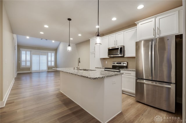 kitchen with white cabinets, stainless steel appliances, a kitchen island with sink, and sink