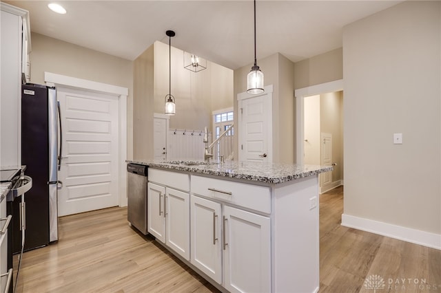 kitchen with a center island with sink, white cabinetry, stainless steel appliances, and hanging light fixtures