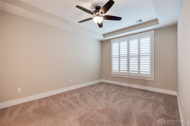 spare room featuring carpet, a raised ceiling, and ceiling fan