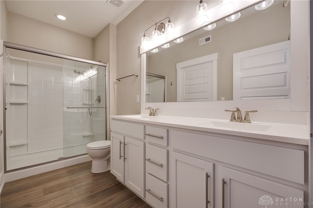 bathroom with hardwood / wood-style floors, vanity, toilet, and a shower with shower door