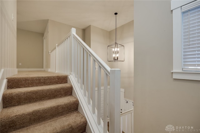 stairway featuring carpet and a notable chandelier