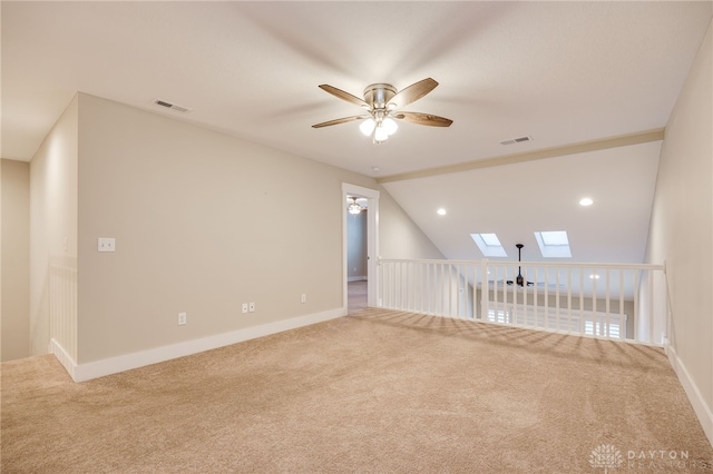 unfurnished room with carpet flooring, ceiling fan, and vaulted ceiling with skylight