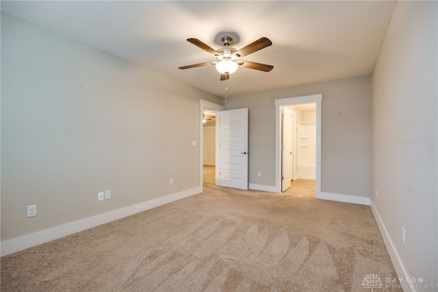 unfurnished bedroom featuring ceiling fan, ensuite bathroom, and light carpet