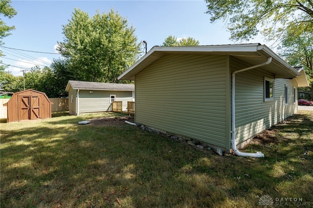 view of side of property featuring a lawn and a storage shed