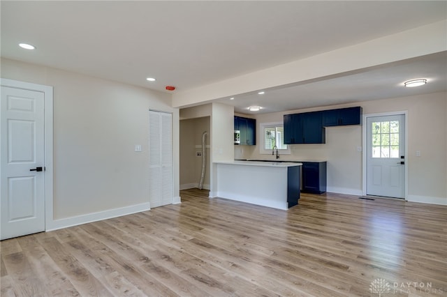 kitchen featuring blue cabinetry, kitchen peninsula, light hardwood / wood-style flooring, and sink