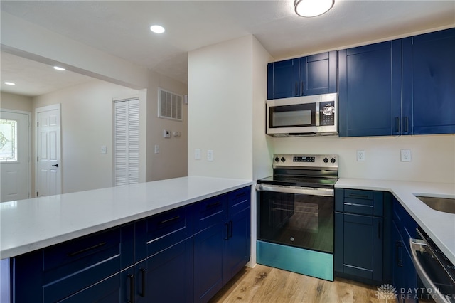 kitchen featuring blue cabinetry, light wood-type flooring, and appliances with stainless steel finishes