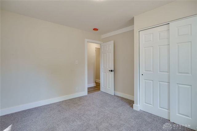 unfurnished bedroom featuring light carpet and a closet