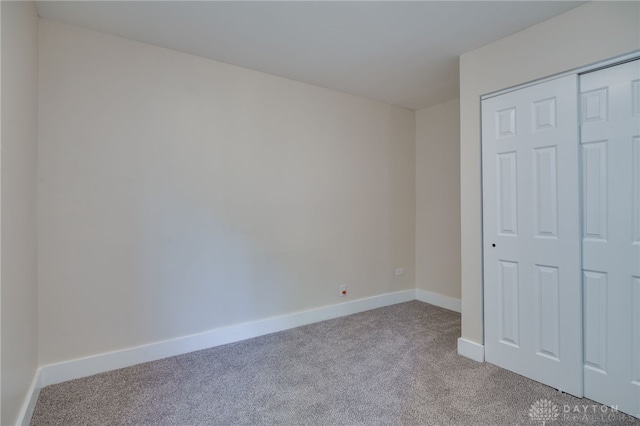 unfurnished bedroom featuring light colored carpet and a closet