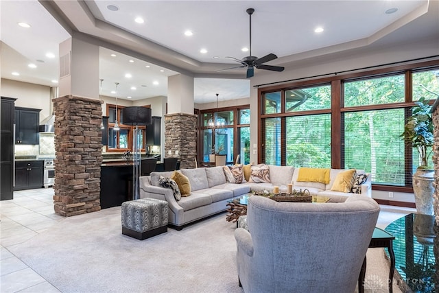 living room with decorative columns, light tile patterned floors, and ceiling fan with notable chandelier