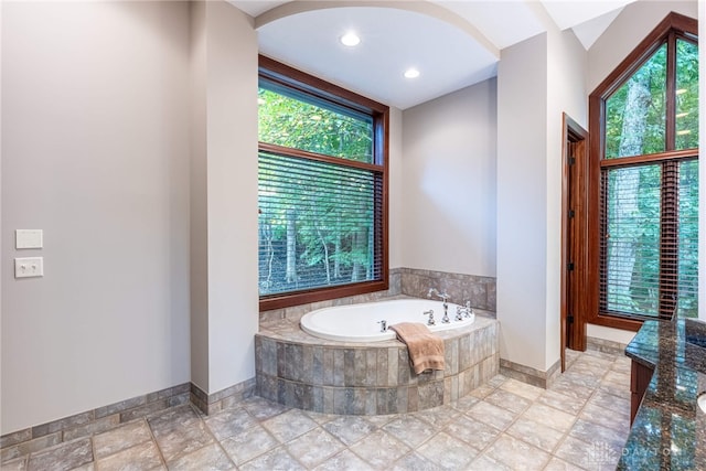 bathroom with a wealth of natural light and a relaxing tiled tub