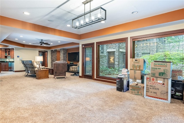 carpeted living room featuring a raised ceiling and ceiling fan