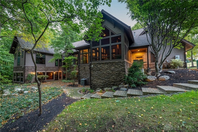 back of house featuring central AC, a lawn, and a sunroom