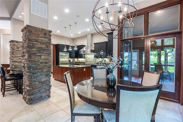 dining space with sink, light tile patterned floors, ornate columns, a towering ceiling, and a notable chandelier