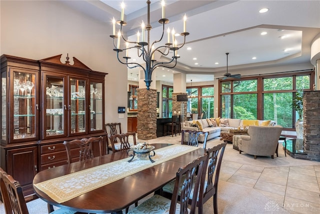 tiled dining room with ceiling fan with notable chandelier and a raised ceiling