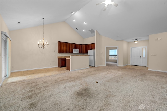 kitchen featuring ceiling fan with notable chandelier, light carpet, a kitchen island, white appliances, and decorative light fixtures