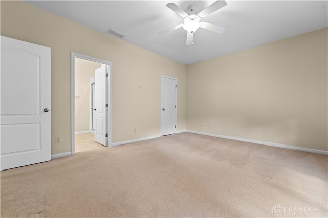 unfurnished bedroom featuring ceiling fan, ensuite bath, and light colored carpet