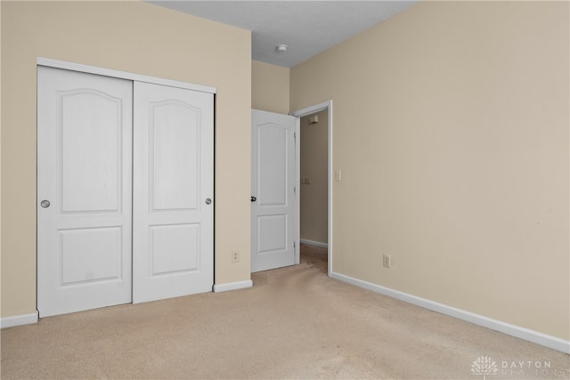 unfurnished bedroom with light carpet and a closet