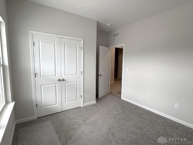 unfurnished bedroom featuring a closet, carpet, and a textured ceiling