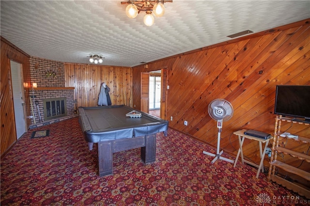 rec room with carpet flooring, wood walls, billiards, and a brick fireplace