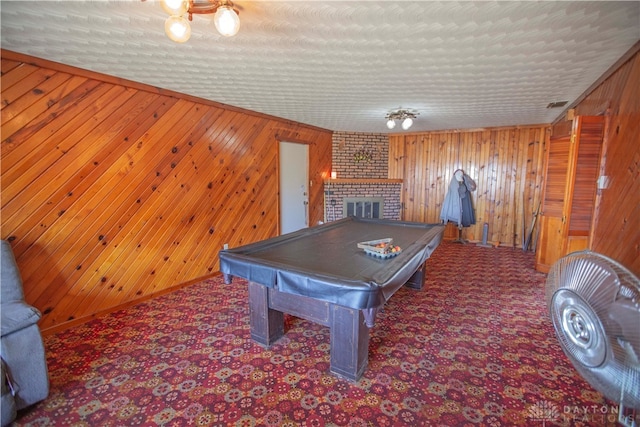 rec room with a textured ceiling, billiards, a fireplace, and wood walls