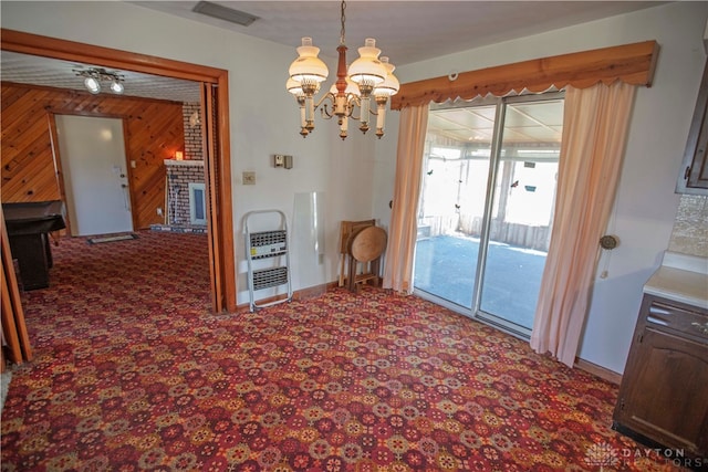 dining room with ceiling fan with notable chandelier, heating unit, wooden walls, and a fireplace