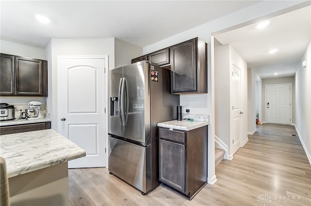 kitchen with stainless steel refrigerator with ice dispenser, dark brown cabinets, and light hardwood / wood-style flooring