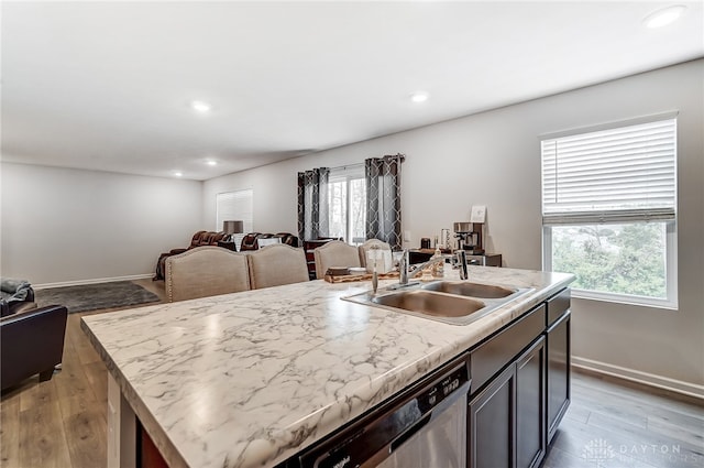 kitchen with sink, a kitchen island with sink, dishwasher, and light hardwood / wood-style flooring