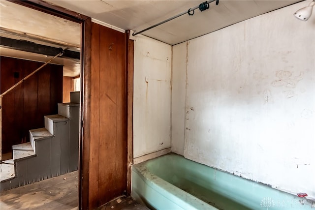 bathroom with a bath and wood walls