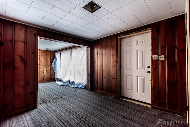 carpeted foyer with wooden walls