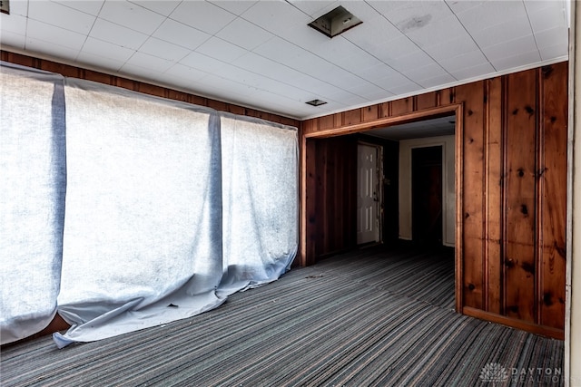 unfurnished room featuring wooden walls