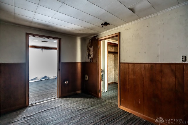 carpeted spare room featuring wooden walls and crown molding