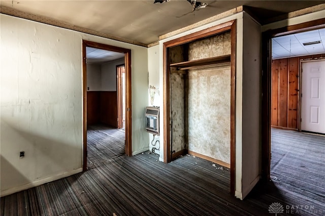 interior space with wood walls, dark hardwood / wood-style floors, and heating unit