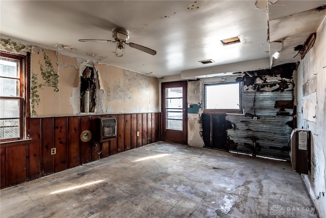 empty room with heating unit, wooden walls, and ceiling fan