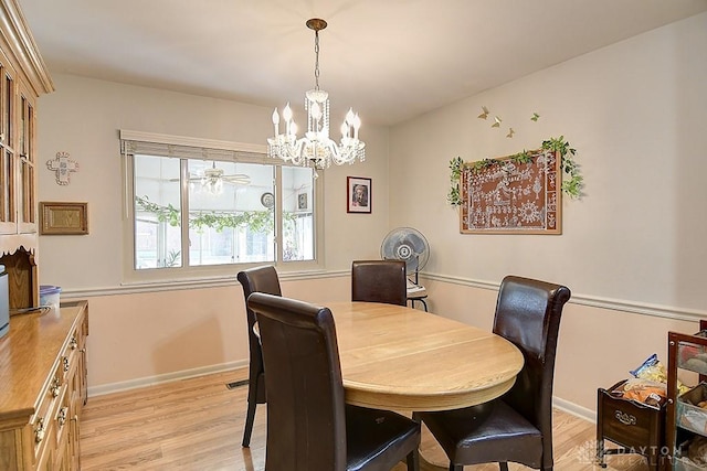 dining area with light wood-style floors, baseboards, and an inviting chandelier