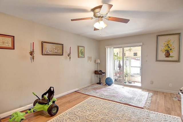 workout area with a ceiling fan, light wood-type flooring, and baseboards