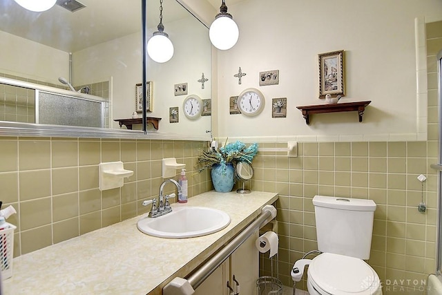 bathroom featuring toilet, visible vents, vanity, wainscoting, and a shower stall