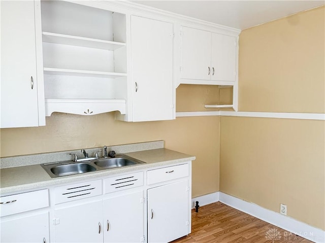 kitchen featuring light wood-type flooring, white cabinetry, and sink