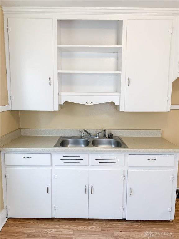 kitchen with white cabinetry, sink, and light hardwood / wood-style floors