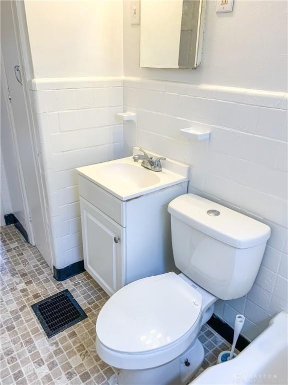 bathroom featuring tile patterned flooring, vanity, tile walls, and toilet