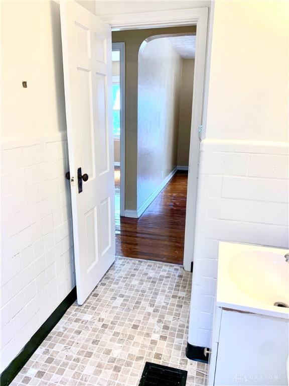 corridor featuring light tile patterned floors, tile walls, and sink