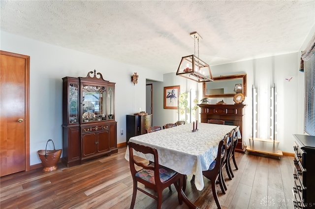 dining room with a textured ceiling and dark hardwood / wood-style flooring