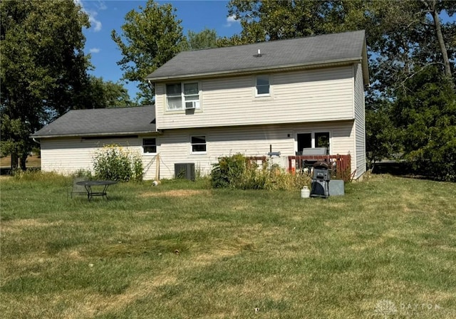 rear view of house with central air condition unit and a lawn