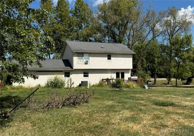 back of property with central AC and a lawn