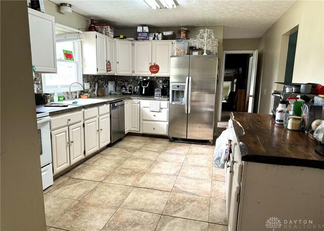 kitchen with appliances with stainless steel finishes, white cabinetry, backsplash, a textured ceiling, and sink