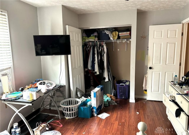 bedroom featuring a textured ceiling, dark wood-type flooring, and a closet