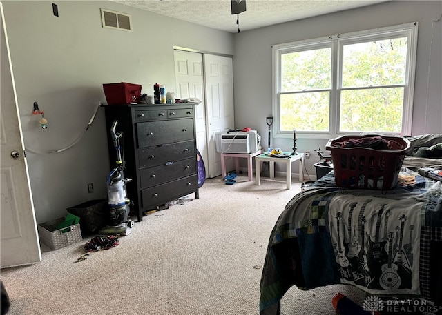 carpeted bedroom featuring a textured ceiling, ceiling fan, and a closet